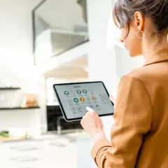 Mujer interactúa con una tablet que muestra la interfaz de un smart gateway para controlar su hogar inteligente.