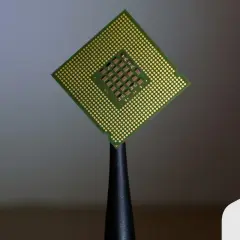 Procesador Intel Core i5, con sus pines dorados y el chip central visible, sostenido por una herramienta.