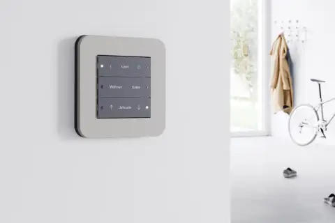 Panel de control moderno con botones para luz, salón y persianas, parte de dispositivos KNX para automatización del hogar.